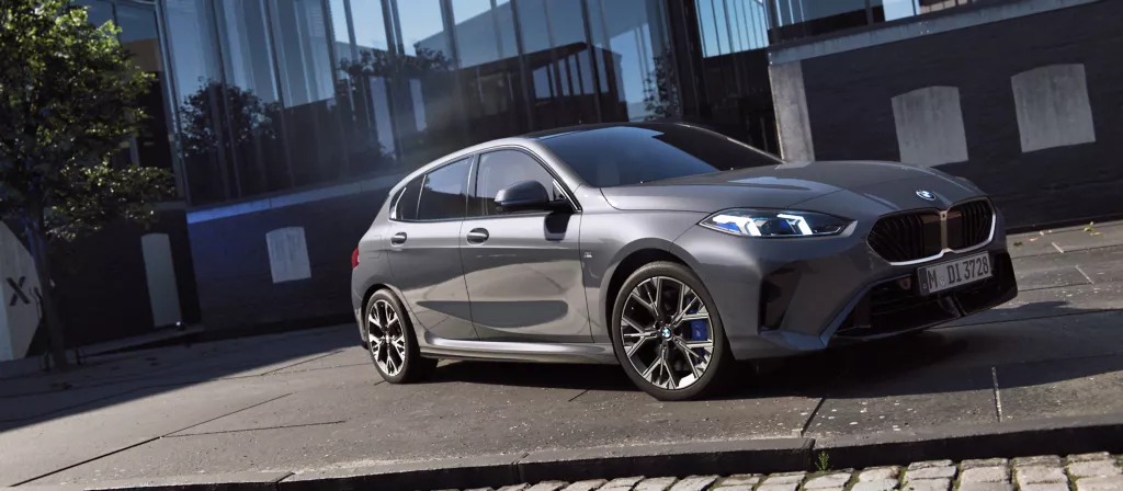 Immagine della BMW Serie 1 120 M Sport Design, di colore grigio metallizzato, su strada parcheggiata. Promozione Gennaio 2025 presso le sedi BMW del Gruppo Brandini a Firenze e Pistoia.