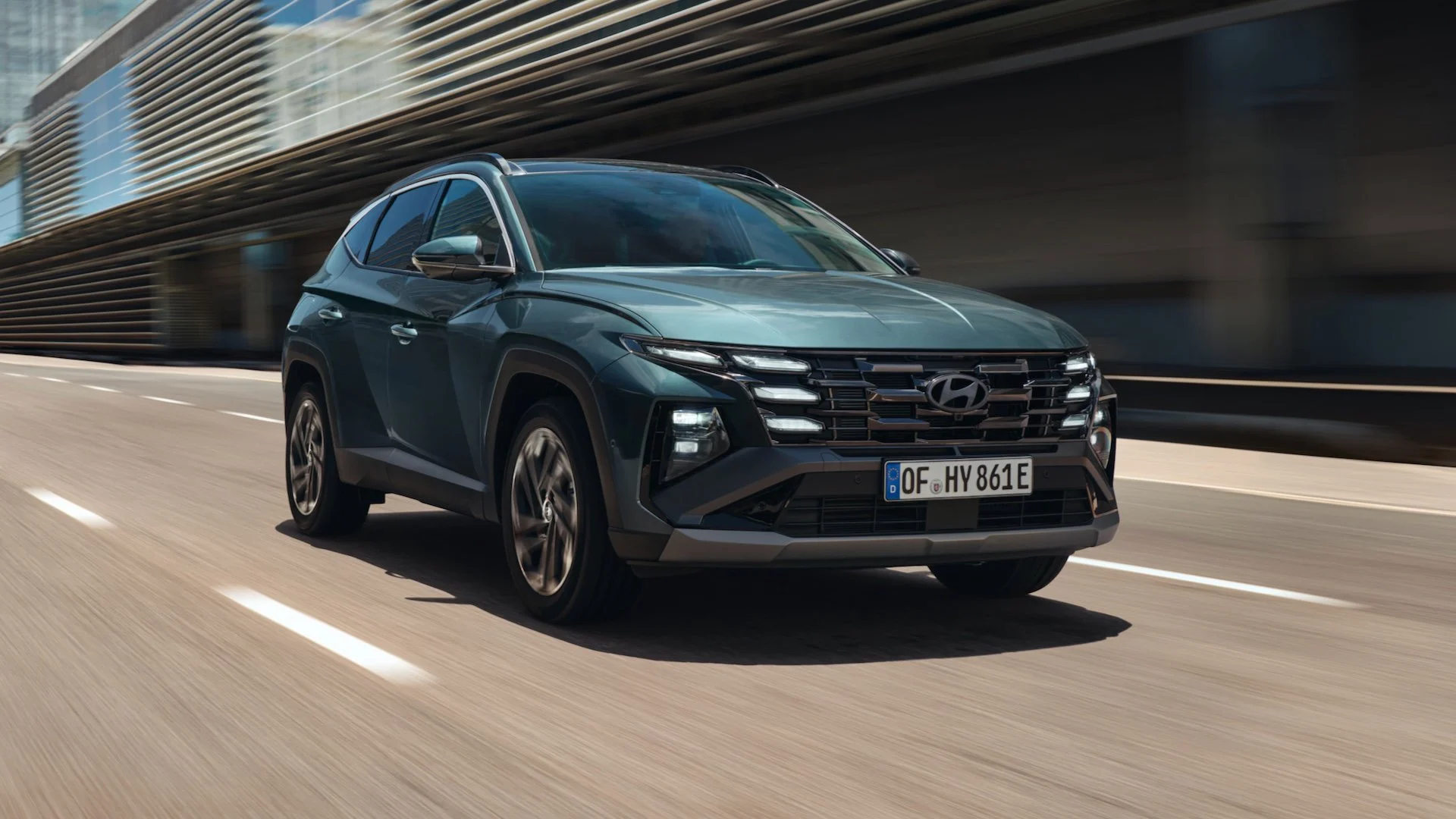 Hyundai Tucson Hybrid 2025 in movimento su strada urbana, un SUV moderno e tecnologico disponibile nelle sedi Brandini a Firenze e Grosseto.