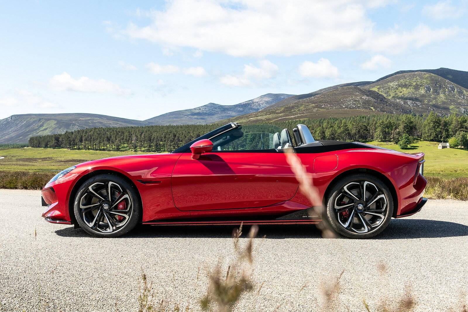 MG Cyberster 2024 cabriolet rossa in un paesaggio naturale, con design sportivo e cerchi in lega aerodinamici, disponibile nella concessionaria Brandini di Grosseto